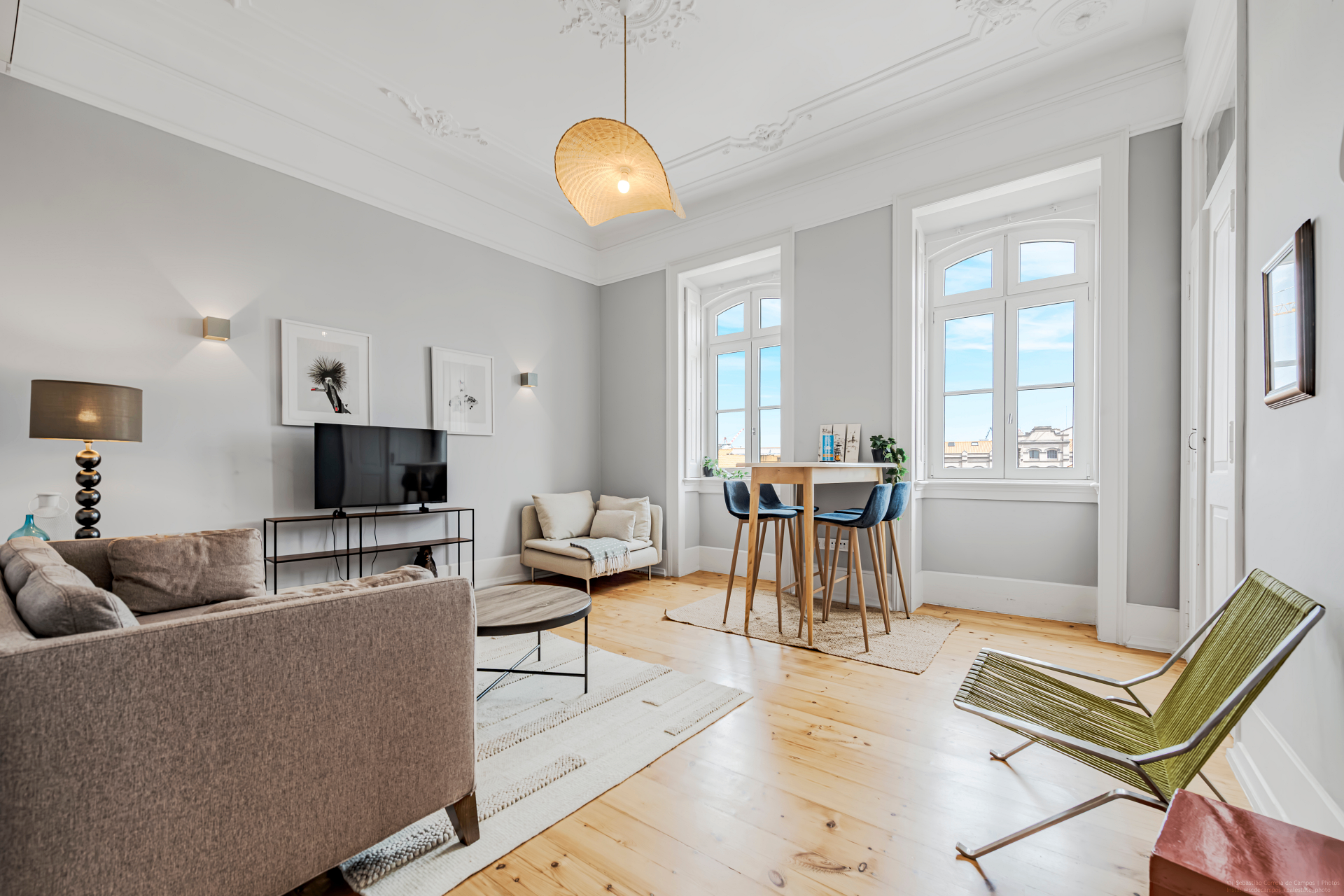 Wide view of the apartment living room with tall windows and dining area
