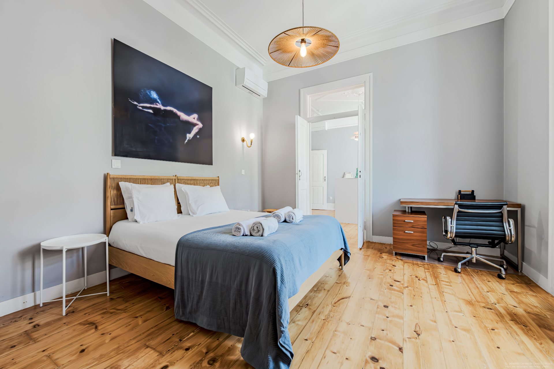 Spacious suite bedroom with grey walls, wooden floor, large bed and artwork