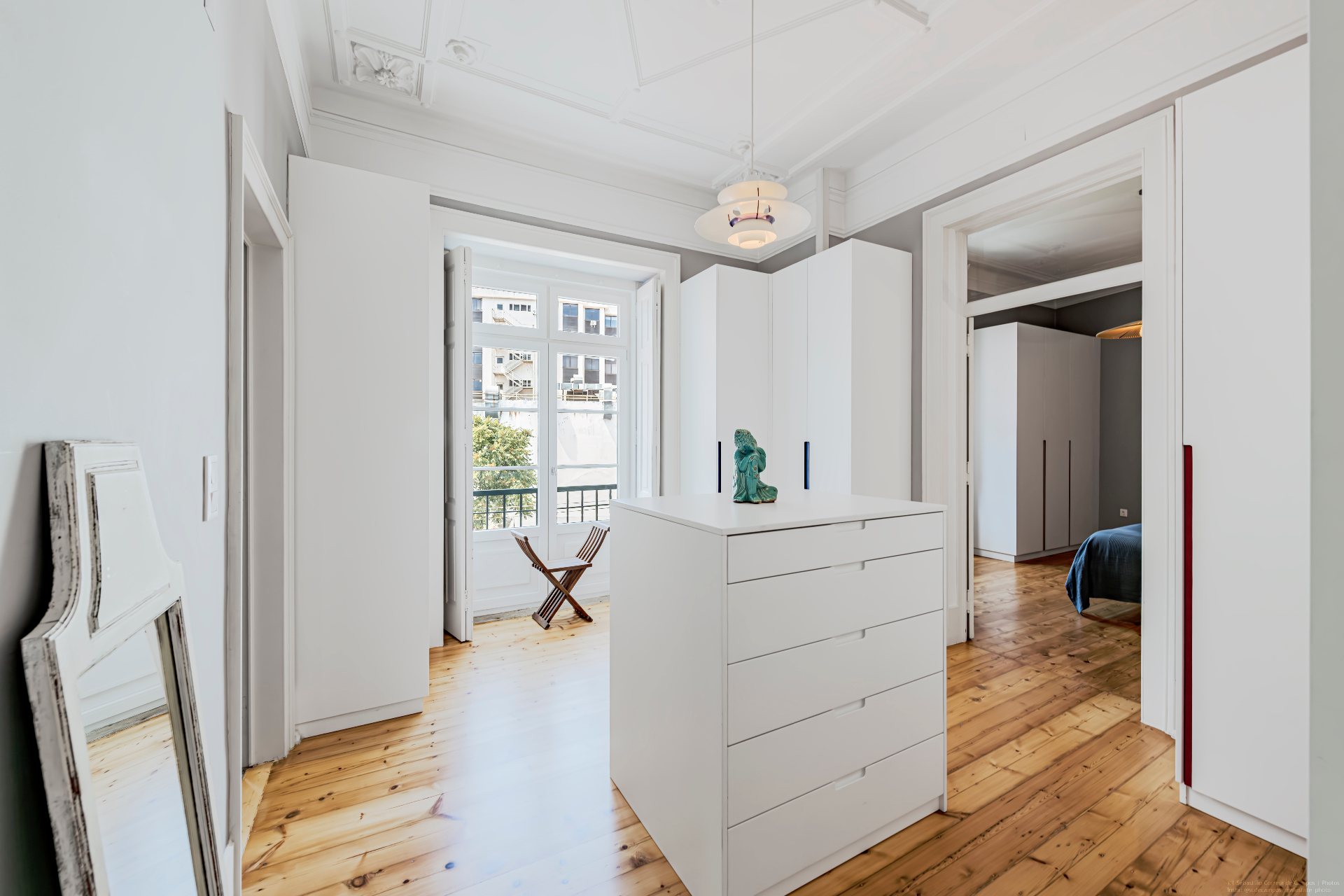Bright dressing area with white wardrobes, original ceiling mouldings and balcony
